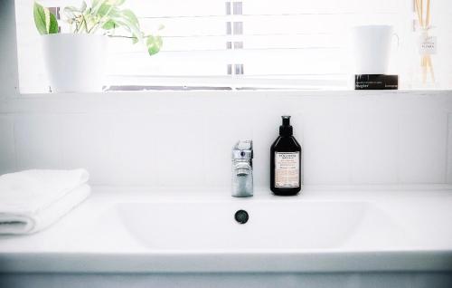 a bottle of alcohol sitting on a bathroom sink at Maison Macquarie in Dubbo