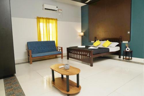 a bedroom with a bed and a couch and a table at Orange valley Town Residency in Trivandrum