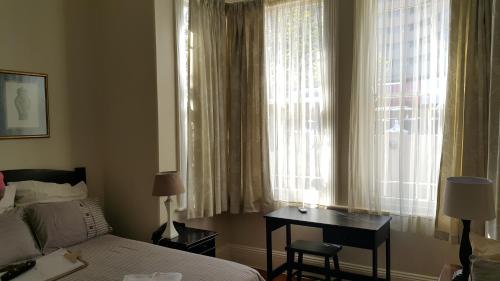 a bedroom with a bed and a desk next to a window at Sommersby Bed & Breakfast in Durban