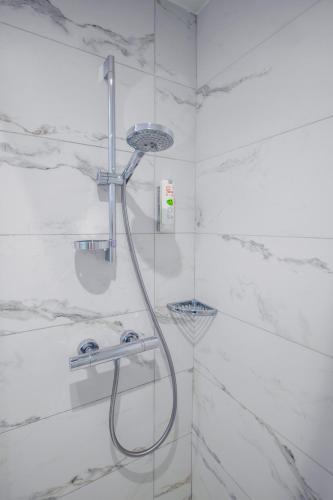 a shower in a bathroom with white marble walls at Cit'Hotel Logis De Brou, Bourg en Bresse RENOVE EN 2026 in Bourg-en-Bresse