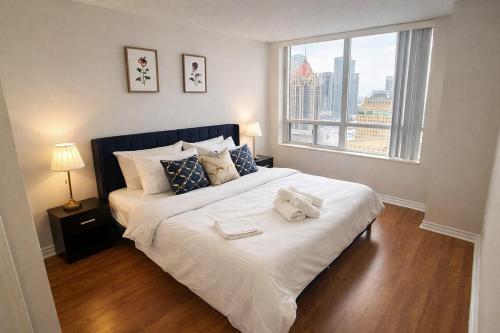 a bedroom with a large white bed with a window at Skyline Retreat Floor-to-Ceiling Views in Mississauga