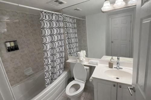 a bathroom with a sink and a toilet and a bath tub at Skyline Retreat Floor-to-Ceiling Views in Mississauga
