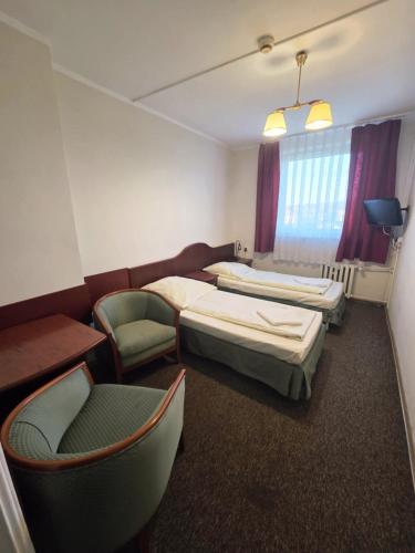 a hotel room with two beds and a chair at Dom Turysty Sanok in Sanok