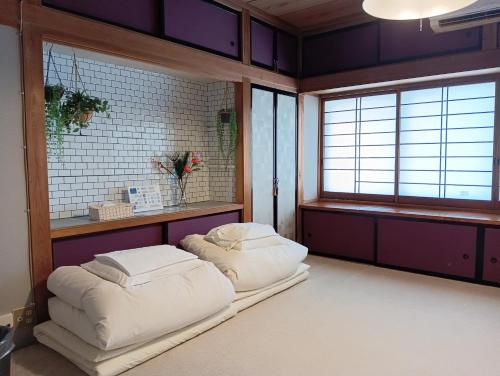 two beds in a room with purple walls and windows at SAMURISE DARUMA in Fujiyoshida