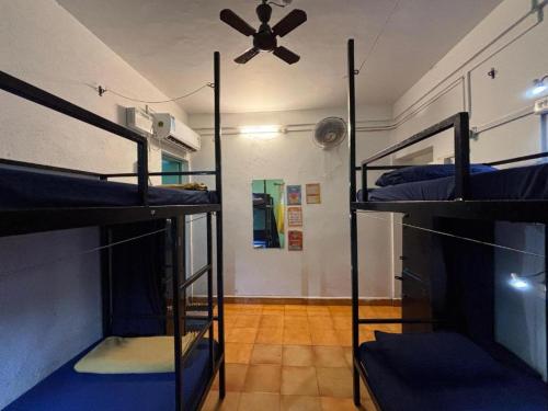 a room with three bunk beds and a ceiling fan at Mandala House - Party hostel in Palolem