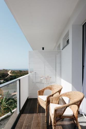 a balcony with wicker chairs and a view of the ocean at O Lugar in Porto Covo