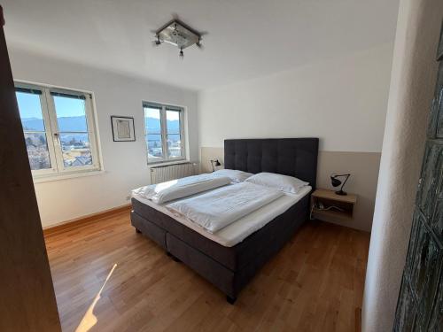 a bedroom with a large bed and two windows at Ferienwohnung Roseggersiedlung in Murau