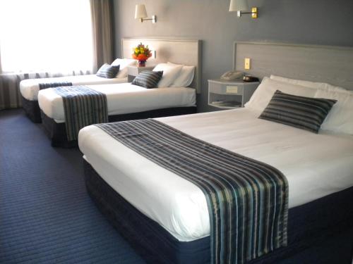 a hotel room with two beds and two lamps at Ibis Styles Adelaide Manor in Adelaide