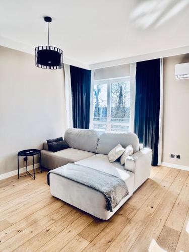 a living room with a white couch and blue curtains at Apartament La Bella klimatyzacja, garaż podziemny, Fv in Suwałki