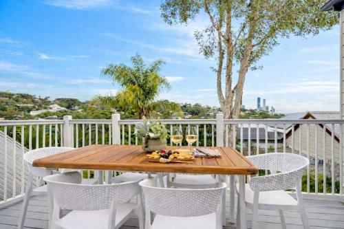 a wooden table on a balcony with chairs and wine glasses at 4 Bed Queenslander City Views Walk to Suncorp Deck + Parking in Brisbane