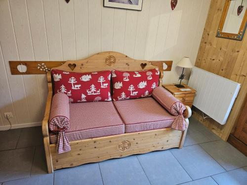 a wooden couch with red and white pillows on it at Chalet La Piste Bleu in Saint-Gervais-les-Bains
