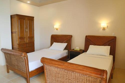 a room with two beds and a cabinet at Turtle Bay Dive Resort in Moalboal