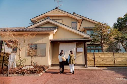 two people walking in front of a house at めぐり宿 庵結 in Shimonoseki