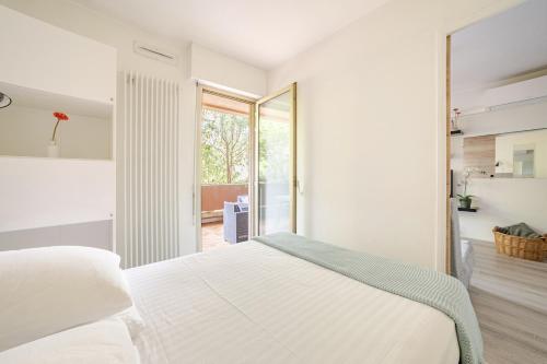 a bedroom with a white bed and a sliding glass door at Appartement calme, clim, patio XXL, piscine&parking in Hyères