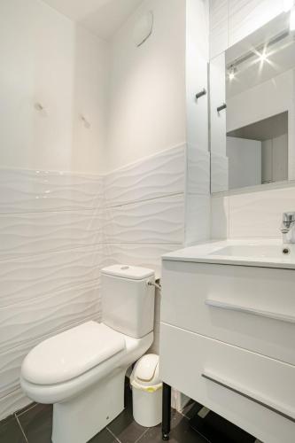 a white bathroom with a toilet and a sink at Appartement calme, clim, patio XXL, piscine&parking in Hyères