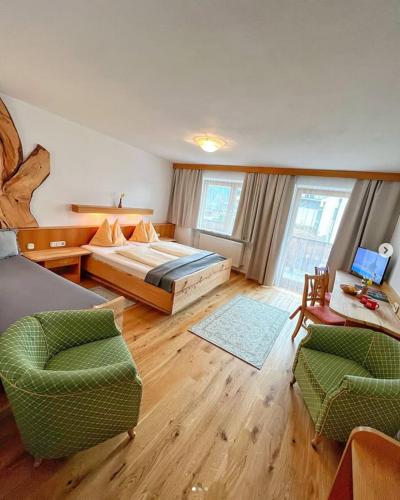 a bedroom with a bed and a couch and chairs at Pension Mayerhofer in Piesendorf