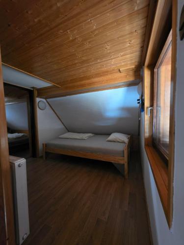 a small bed in a room with a wooden ceiling at Tijekova koča in Hočko Pohorje