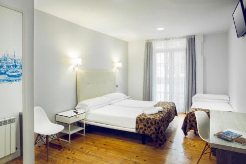 Habitación de hotel con 2 camas y escritorio en Casual Gurea en Bilbao