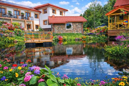 a pond in a garden with flowers and buildings at Edelweiss Vila Šventoji in Šventoji