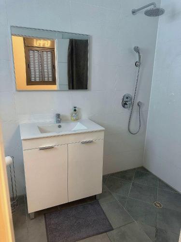 a white bathroom with a sink and a shower at Penthouse à Manhattan Netivot in Netivot