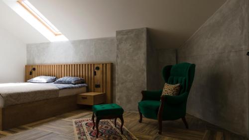 a bedroom with a bed and a green chair at Avala apartments in Beli Potok