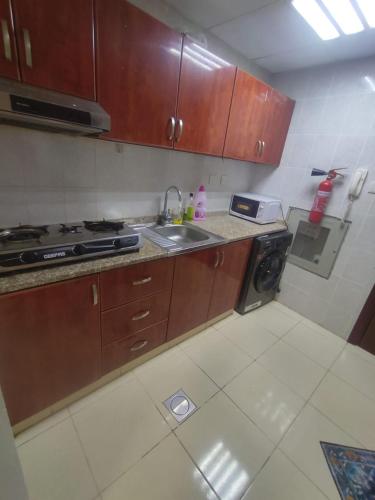 a kitchen with wooden cabinets and a sink and a stove at Cozy Studio In Orient Towers Ajman in Ajman 
