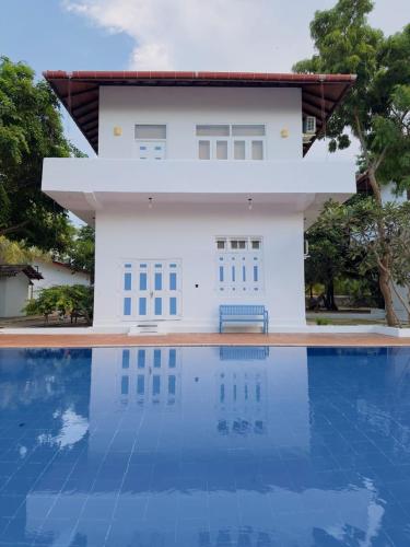 a villa with a swimming pool in front of a house at Blue Kite Retreat in Kalpitiya