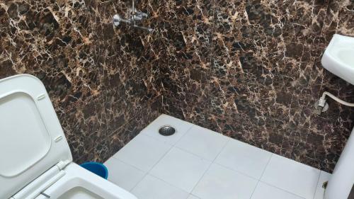 a bathroom with a toilet and a marble wall at Hotel rishav prime in Ghaziabad