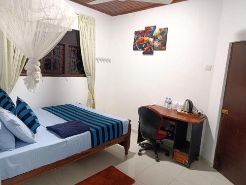 a bedroom with a bed and a desk with a computer at Zion Haven Villa in Tangalle