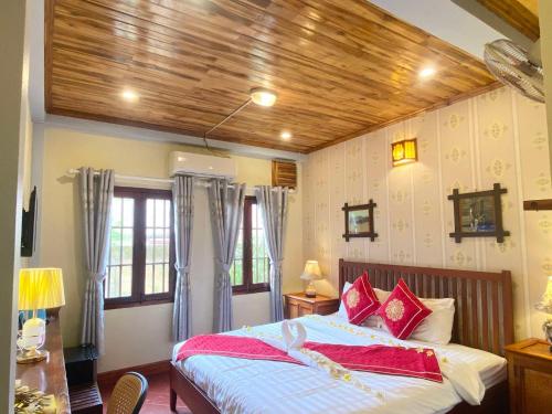 a bedroom with a large bed with red pillows at Golden Sun Hotel Luang Prabang in Luang Prabang