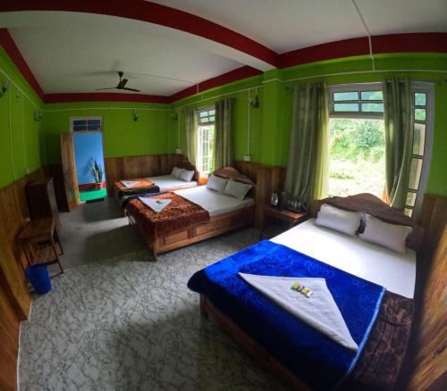 a bedroom with two beds in a room with green walls at Hobo's Nest in Kurseong