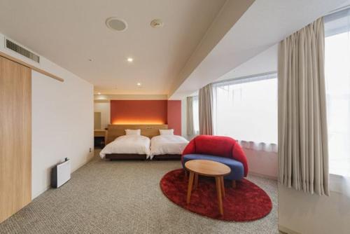 a bedroom with a bed and a red chair at Awa Kanko Hotel in Tokushima
