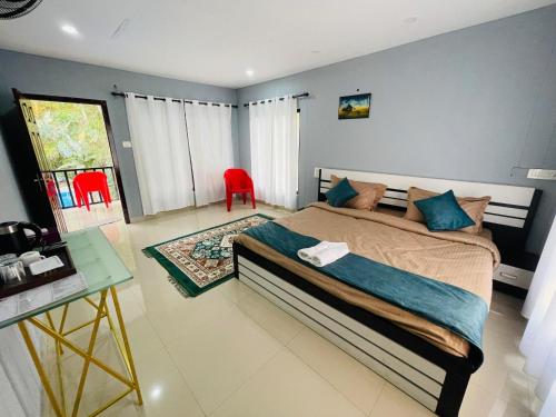 a bedroom with a bed and a table and red chairs at Stillora Hotel And Resorts in Sultan Bathery