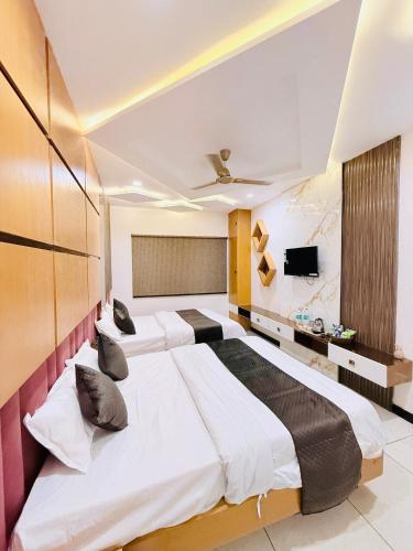 two beds in a hotel room with a tv at Hotel Hira Palace in Ujjain