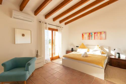 a bedroom with a bed and a chair at Idyllische Natur-Finca mit 12m Pool & Meerblick in Porto Cristo
