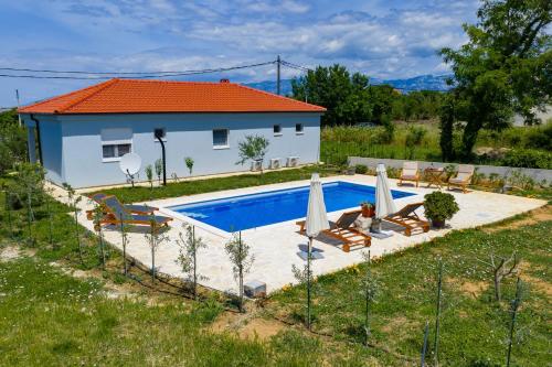 a villa with a swimming pool in front of a house at Pomalo in Vrsi