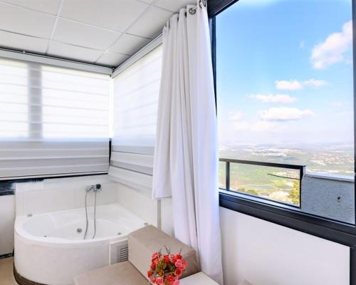 a bathroom with a bath tub and a window at האלפים של הכרמל ומצפה העמקים- וילה ומלונית מול נוף הצפון in Talpiyyot