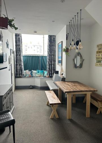 a living room with a table and bench and a window at Cosy 2 Bedroom Coastal Retreat with Sea Views and a Private Indoor Hot Tub in Margate