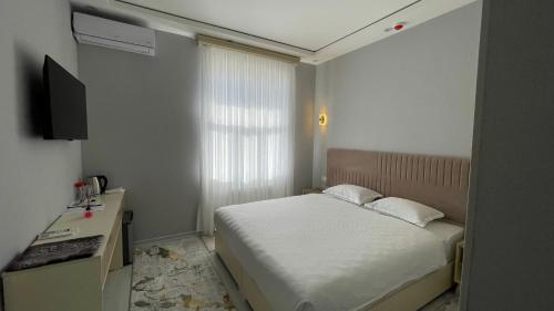 a small bedroom with a bed and a television at Bahrom Boutique Hotel in Khiva