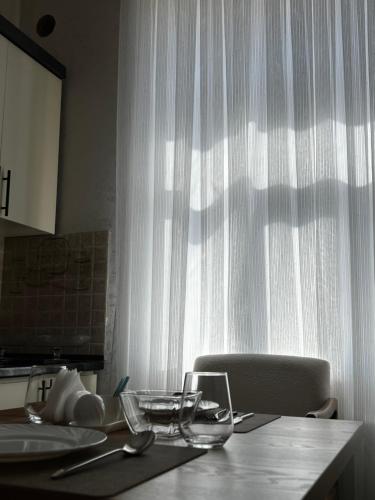 a kitchen with a table with a window with white curtains at Bahrom Boutique Hotel in Khiva