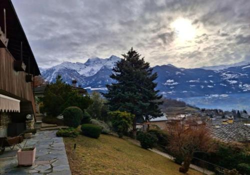 a house with a tree and a view of mountains at La maison de Carmen in Aosta