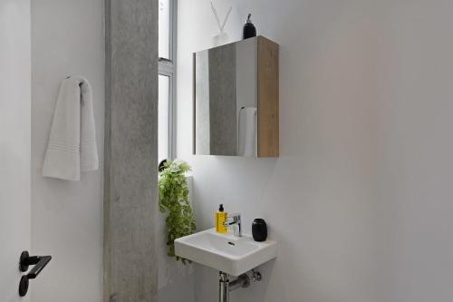 a white bathroom with a sink and a mirror at SIX ON N - Fluent Serviced Apartments in Cape Town