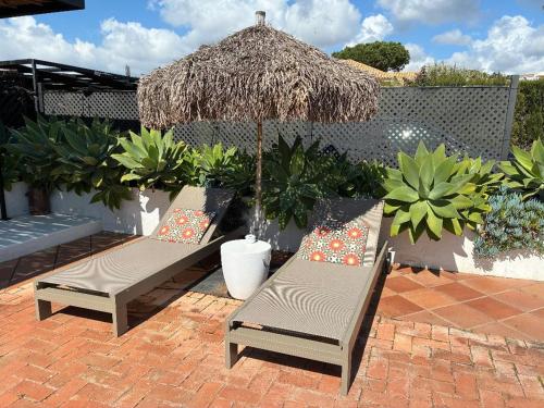 two chairs and an umbrella on a brick patio at Casa Junto a la Playa in El Rompido