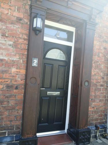 a black door on the side of a brick building at The Bishop Bolthole in Bishop Auckland