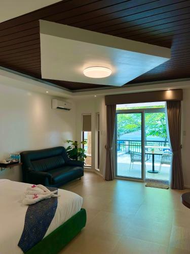 a bedroom with a bed and a couch and a balcony at Castle View Hotel Samal in Magamomo
