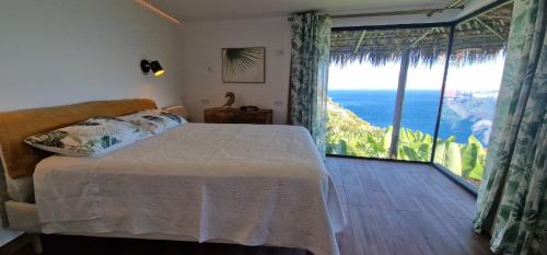 a bedroom with a bed and a view of the ocean at Torre Bella Gardens in Arco da Calheta