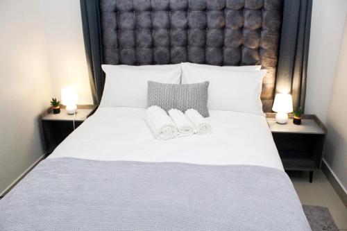 a bedroom with a large white bed with two slippers at The Millennial, Secure parking, 3 mins to Gateway in Durban