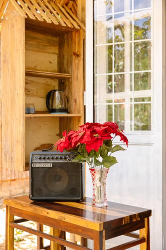 a vase with red flowers sitting on a table with a television at Làng Hương Village in Teurnoum