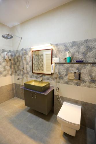 a bathroom with a sink and a toilet and a mirror at Le Clarisse Guest House in Pondicherry