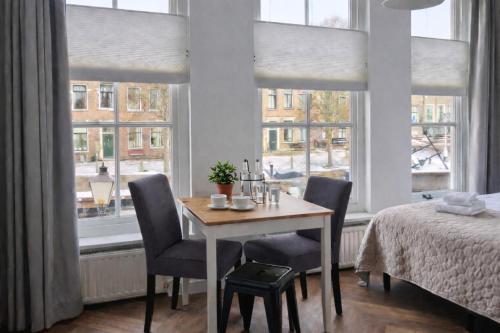 a dining room with a table and chairs and windows at Boutique Hotel De Grote Kade in Goes